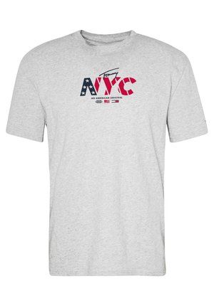 T-shirt gris clair avec le texte « Tommy NYC » dans un motif étoiles et rayures, et « An American Original » imprimé sous le logo.