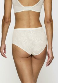 Ropa interior de talle alto color crema con un patrón texturizado ondulado y una cinturilla elástica suave. Presenta un diseño de parte trasera sin costuras.
