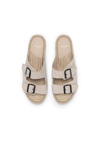 Sandales en suede beige clair avec deux sangles à boucle noires et une semelle en jute tressé. Design plat et bout ouvert pour un enfilage facile.