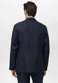 Sacou bleumarin cu croială ajustată, rever simplu cu decupaj, și mâneci lungi. Textură netedă, design minimal și detalii curate de cusătură.