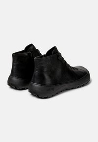 Pair of black leather ankle boots with side zippers, laces, and textured soles displayed on white background.