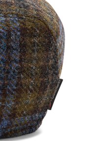 Wełniana czapka typu flat cap w kratę w odcieniach brązu i niebieskiego, z teksturowaną powierzchnią i małą materiałową metką po boku.