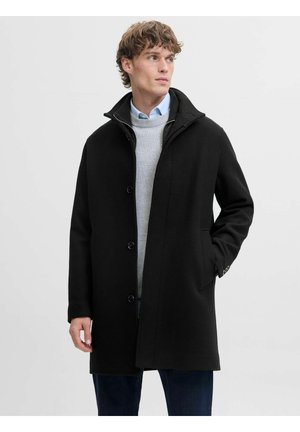 Schwarzer Wollmischungs-Mantel mit hohem Kragen, vorderen Knöpfen und seitlichen Taschen. Getragen über einem grauen Pullover und einem blauen Hemd, das ein strukturiertes Design aufweist.