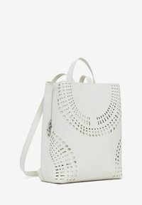 Zaino bianco in pelle con motivo a intaglio, chiusura a zip, due manici superiori e una tracolla laterale regolabile per opzioni di trasporto versatili.