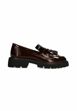 Donkerbruine glanzende loafer met een dikke zwarte zool en tassel-detail bovenop, zijaanzicht op witte achtergrond.