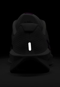 Bottine de sport avec une tige grise texturée, dotée d'une bande réfléchissante blanche au talon, d'accents violets et d'un col rembourré.