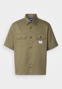 Short-sleeve olive green shirt with button-up front, two chest pockets, and a tag on the left pocket. Made of a smooth fabric.