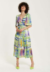 Multicolored midi dress features a wrap design with short sleeves, made of lightweight fabric. Accented with a flared skirt and vibrant abstract patterns.