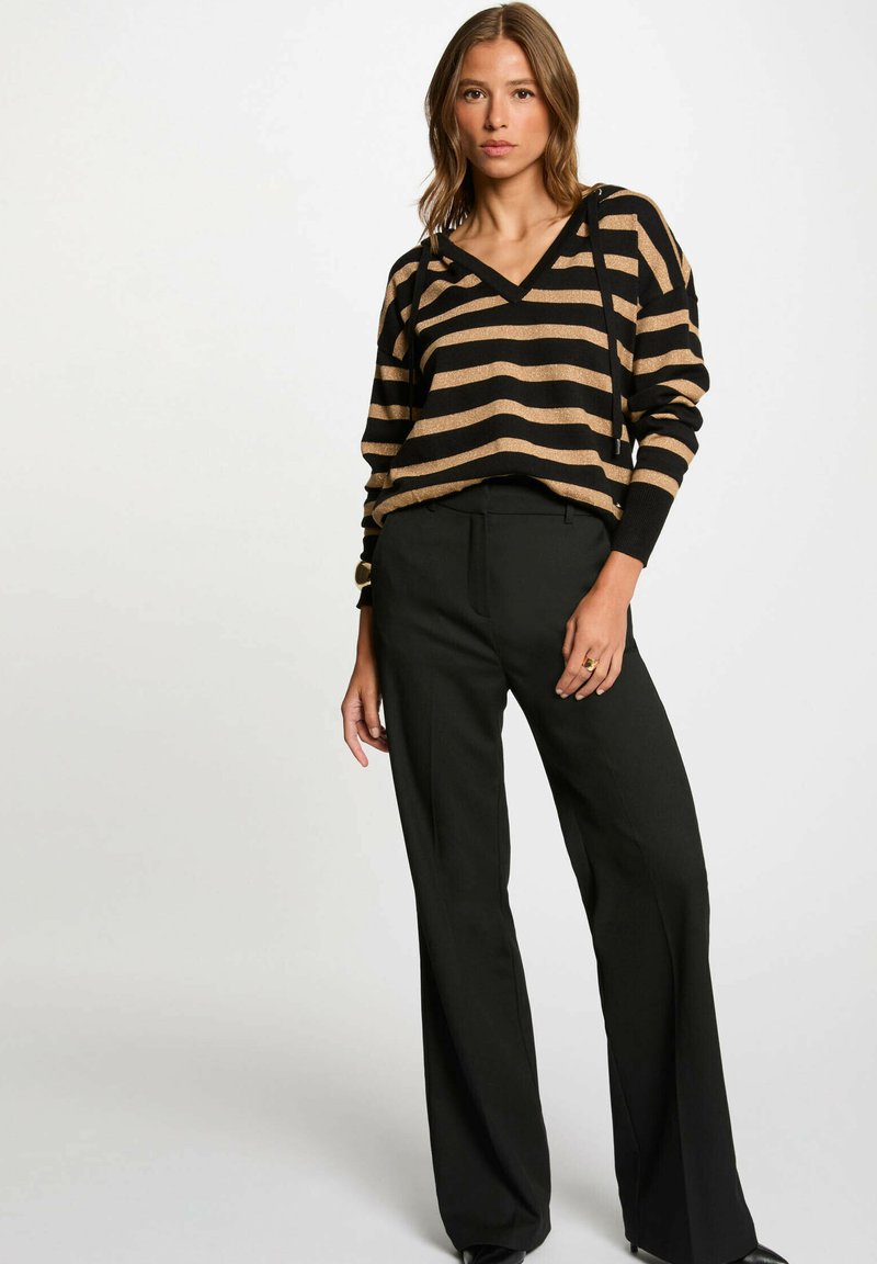 Maglione a righe nero e oro in maglia, con scollo a V e maniche lunghe, abbinato a pantaloni neri a vita alta con taglio a gamba dritta.