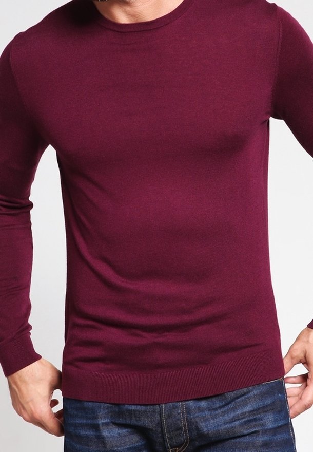 Burgundy långärmad tröja tillverkad av slät stickad textil, med rund halsringning och åtsittande muddar, tillsammans med denimjeans.