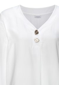 Weiße Bluse mit V-Ausschnitt. Verfügt über zwei markante hellbraune Knöpfe am Ausschnitt und glattes, weiches Stoffmaterial mit einem leichten Glanz.