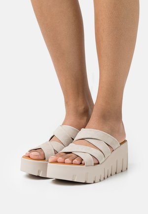 Sandales à plateforme en daim beige avec plusieurs brides croisées et une semelle épaisse et texturée avec des rainures pour une meilleure adhérence.