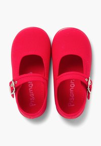 Zapatos Mary Jane de lona roja con correa al tobillo y hebilla plateada. Con lados abiertos y plantilla acolchada. Tejido texturizado con detalles de costura visibles.