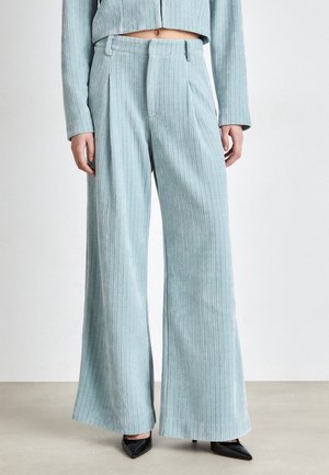 Lichtblauwe, hooggetailleerde, wijde broek met subtiele verticale structuur, gedragen met een bijpassend cropped jasje en zwarte puntige hakken.