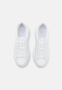 Sneakers bianchi realizzati in materiale sintetico liscia, con punta rotonda, lacci piatti e un logo discreto sulla linguetta.