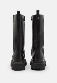 Bottines en cuir noir avec une texture lisse, dotées d'une tige haute, d'une fermeture éclair sur le côté et d'un détail de marque le long des coutures. Semelles en caoutchouc épaisses.