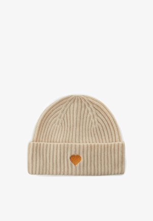 Bonnet en maille de couleur beige clair avec une texture côtelée, featuring un petit cœur orange sur le revers. Matériau doux pour la chaleur.