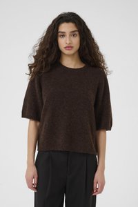 Pull en tricot marron surdimensionné à manches courtes, décolleté rond et finition texturée. Porté avec un pantalon noir taille haute.