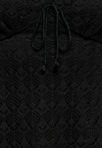 Tissu crochet noir avec motifs en losange et en éventail, doté d'un cordon tressé avec des extrémités à pompons au centre supérieur.