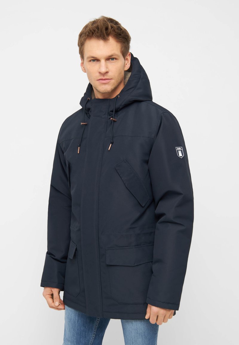 Parka impermeabile blu navy con cappuccio, dotata di chiusura a zip, coulisse regolabili e multiple tasche. Tessuto liscio e design minimalista.