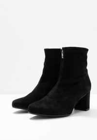 Sorte suede ankelstøvler med spids tå, indvendig lynlås og en robust blokhæl. Glat tekstur og sømløse design detaljer.