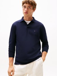 Polo de manga longa azul-marinho com colarinho e um pequeno logotipo no peito. O tecido parece suave, com um design ajustado e punhos canelados.