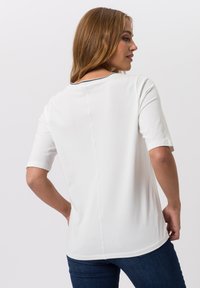 White short-sleeve t-shirt with a round neckline and contrasting navy stitching along the collar. Soft cotton fabric, relaxed fit.
