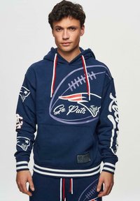 Mörkblå hoodie med fotbollsgraphics, texten "Go Pats" och lagets logotyp. Har röda dragsko, randiga muddar och en känguruficka.