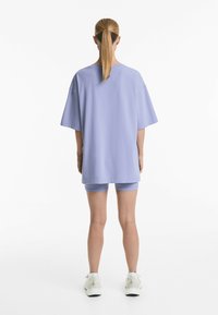 Světle fialové oversized tričko spárované s odpovídajícími šortkami. Vyrobeno z měkké látky, s uvolněným střihem a krátkými rukávy.