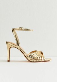 Sandal con tacco alto in oro, caratterizzato da intricate cinghie intrecciate, una cinghia alla caviglia con fibbia e un design a punta elegante.