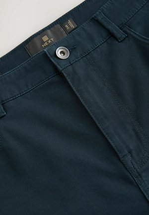 Mörkblå byxor gjorda av en blandning av bomull med en slät textur, med en metallknapp och en subtil sömdesign.