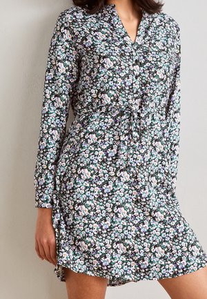 Robe florale noire avec des manches longues, un buste à boutons, une taille à cordon et une coupe fluide. Présente des motifs de fleurs violettes, blanches et vertes.