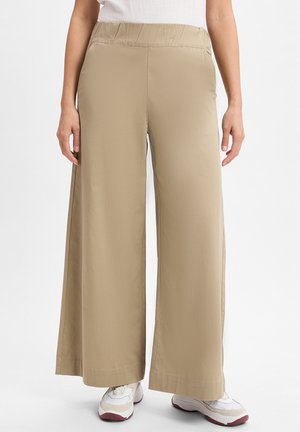 Beige, weit geschnittene Hose aus glattem, leichtem Stoff. Sie verfügt über einen elastischen Bund und Seitenschlitze am Saum für zusätzlichen Komfort.