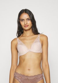 Helle rosa Unterwäsche mit Spitzendetails, weichem Finish und Unterstützung durch Bügel. Verzierte Akzente befinden sich in der Mitte und an den Trägern.