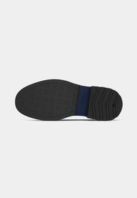 Black rubber shoe sole with a textured diamond pattern and a blue accent at the heel, featuring a flat design and slight arch.