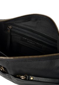 Interno di una borsa in pelle nera con una tasca con zip e numerosi scomparti. Caratterizzata da zip e accessori in tonalità dorata e da una texture liscia.