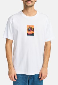 White cotton t-shirt featuring a colorful graphic print of a skull within a rectangular frame, detailed with vibrant pink, orange, and blue accents.