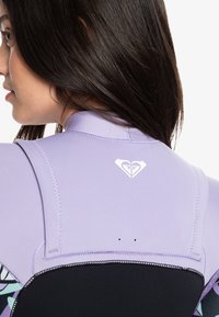 Neopreno morado con sección inferior negra, que presenta un logo de corazón y detalles en las costuras. Patrones visibles en los lados.