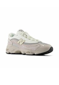 Vaaleanharmaat urheilukengät, joissa on verkko-, nappapinta- ja nahkamateriaaleja. Varusteena on näyttävä "N"-logo, nauhat ja teksturoitu pohja.