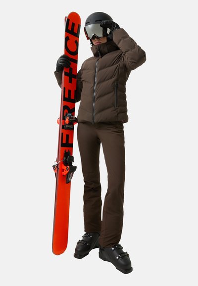 Braune Pufferjacke und -hose, schwarzer Helm und Handschuhe, hält ein orangefarbenes Snowboard mit schwarzen Akzenten. Schlankes Design, funktional für das Skifahren.