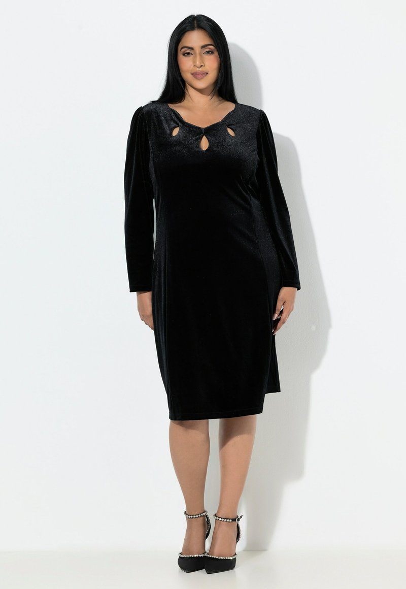 Černé sametové šaty s vypasovaným střihem, dlouhými nabíranými rukávy a výřezem ve tvaru klíčové dírky na výstřihu. Látka má jemný lesk.