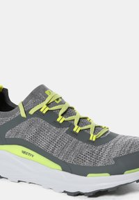 Zapatillas deportivas grises con una parte superior de malla texturizada, cordones de neón amarillos y una suela blanca acolchada con acentos verdes.