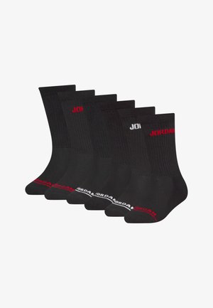 Ensemble de cinq paires de chaussettes en coton noir avec texture côtelée. Présente le logo "JORDAN" en rouge et blanc sur les bordures. Design standard mi-cheville.