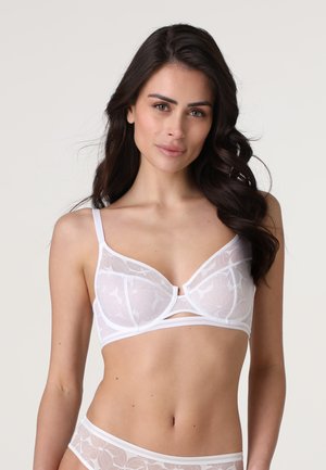 Reggiseno bianco con sovrapposizione di pizzo floreale, supporto con ferretto, spalline regolabili e una fascia liscia con un dettaglio a chiave al centro.
