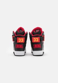 Baskets montantes noires avec des accents rouges et une semelle blanche. Comprend une bride ajustable, le numéro embossé "33" et le logo "EWING".