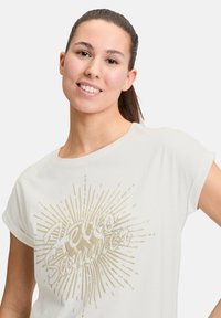 T-shirt blanc à manches courtes avec un graphisme de soleil doré et le texte "Hello Summer" dans une police ludique. Tissu doux avec une coupe décontractée.