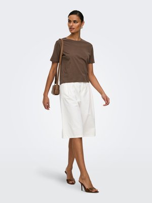 Woman walking in brown short-sleeve top, white knee-length skirt, brown heeled sandals, and carrying small brown shoulder bag.