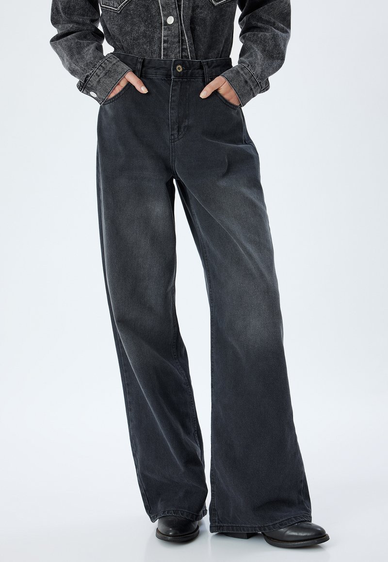 Breda ben, mörkgrå denimbyxor med hög midja, sidofickor och knappstängning. Tyget har en lätt urtvättad textur.