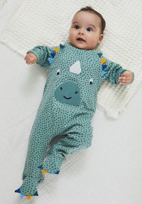 Tutina turchese con pois, caratterizzata da un volto di dinosauro e pinne, con accenti a contrasto in blu, arancione e verde, tessuto morbido al tatto.