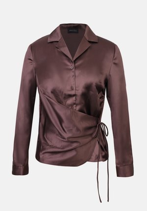 Pruun satiinist pluus, millel on mähkdisain, pikkade varrukatega, sälguga krae ja külgtierdeline detail. Omab nööpidega sulgemist ja siledat tekstuuri.